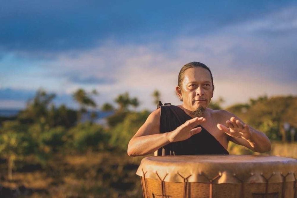 Taro farmer and cultural practitioner Kane Turalde plays the pahu (drum) during a ceremony at Kāneiolouma. Two phases of the restoration have been completed, but much remains.